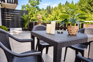 An outdoor patio with a table, chairs, and a potted plant.