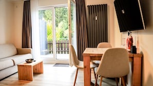 Een moderne woonkamer met een bank, een houten salontafel en een eetgedeelte met een tafel en stoelen.