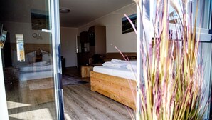 Een moderne slaapkamer met een houten bed, een klein nachtkastje en een bijzettafeltje. Er is een raam met uitzicht op de omgeving.