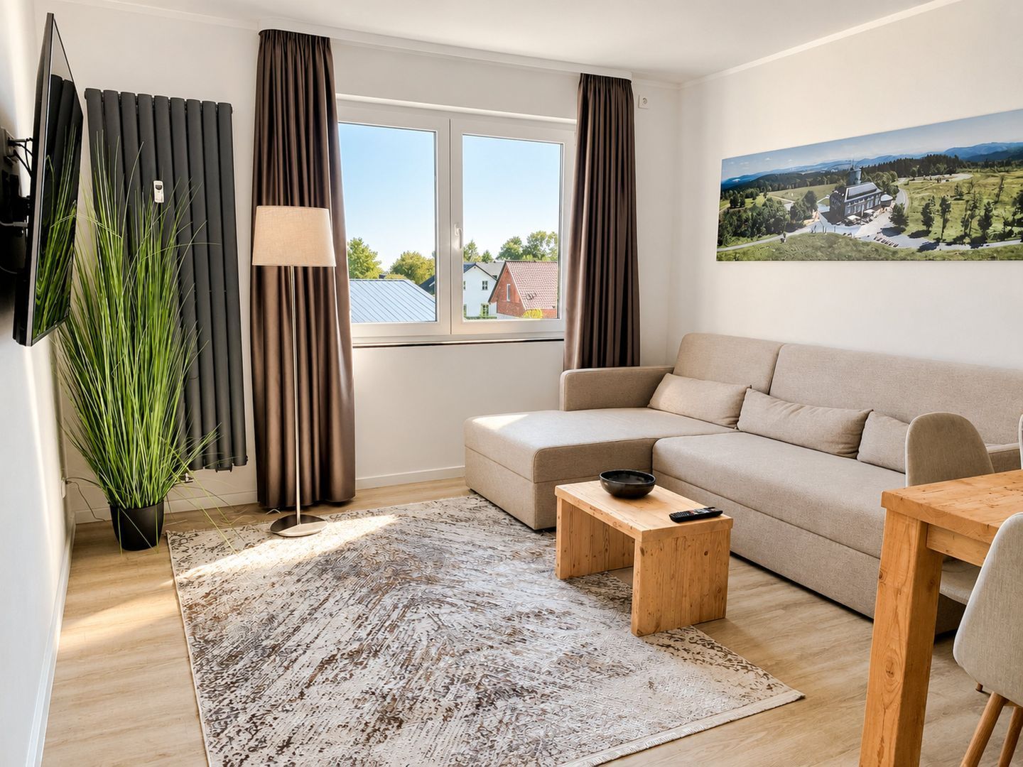 Un salon moderne avec un canapé, une table basse, un téléviseur et une grande fenêtre avec des rideaux.