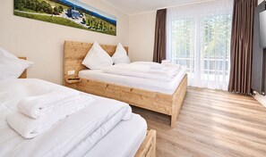 A hotel room with two beds, a wooden headboard, a large window with curtains, and a painting on the wall. - Smart Resorts - Haus Azur - Ferienwohnung 805, Max. 5 Personen - Smart Resorts Haus Azur (Winterberg)