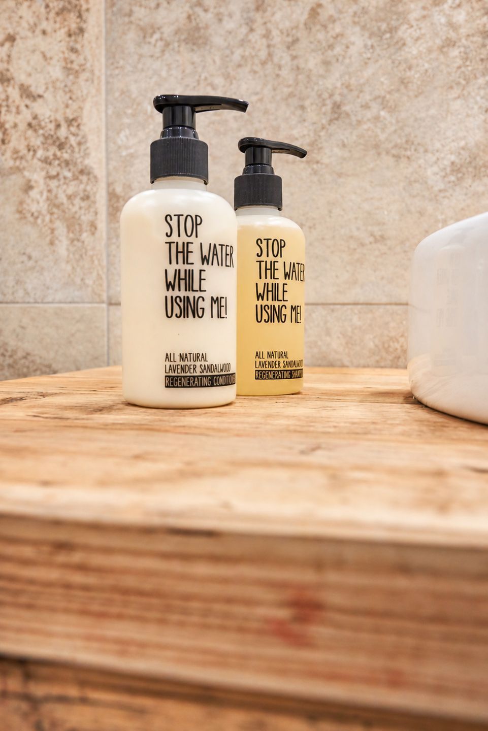 Two bottles of natural lavender and sandalwood regenerating conditioner on a wooden surface.