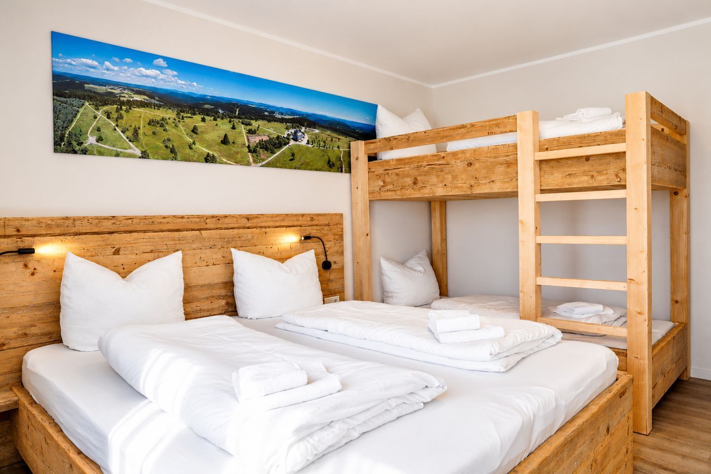 A bunk bed room with white bedding and a painting of a landscape on the wall.