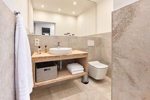 Une salle de bain moderne avec un meuble-lavabo en bois, un lavabo blanc et des toilettes.