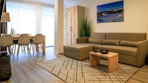 Een moderne woonkamer met een bank, een salontafel en een eethoek met stoelen en een tafel.