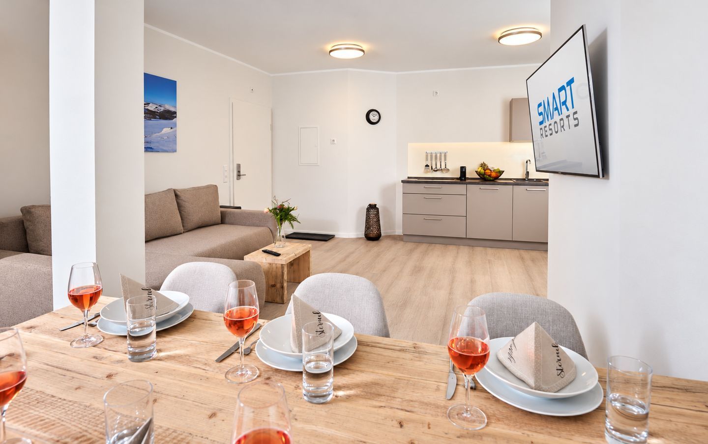 A modern living room with a dining area, a kitchen, and a view of a mountain.