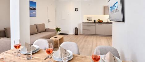 Una sala de estar moderna con comedor, cocina y vistas a la montaña.