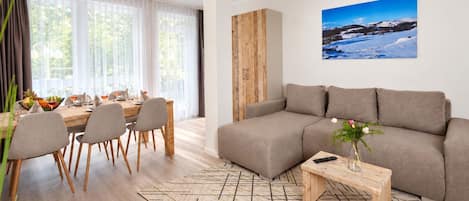 Una sala moderna con un sofá seccional, una mesa de comedor y sillas.
