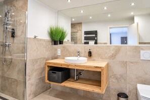 A modern bathroom with a glass shower enclosure, a wooden vanity with a sink, and a mirror above.