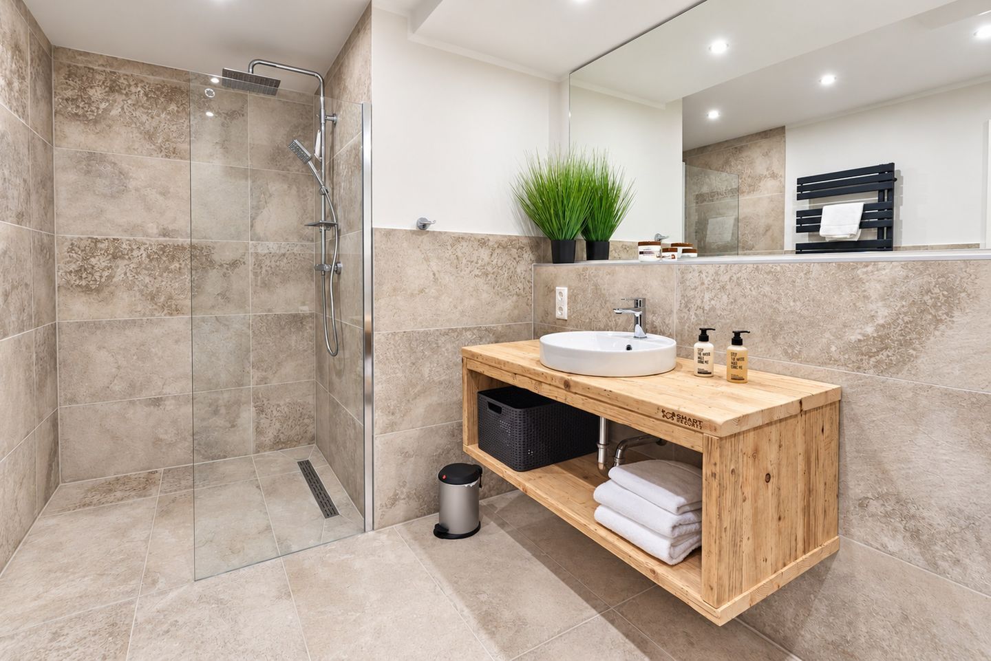 Une salle de bain moderne avec une douche à parois de verre, un meuble-lavabo en bois et un miroir au-dessus.