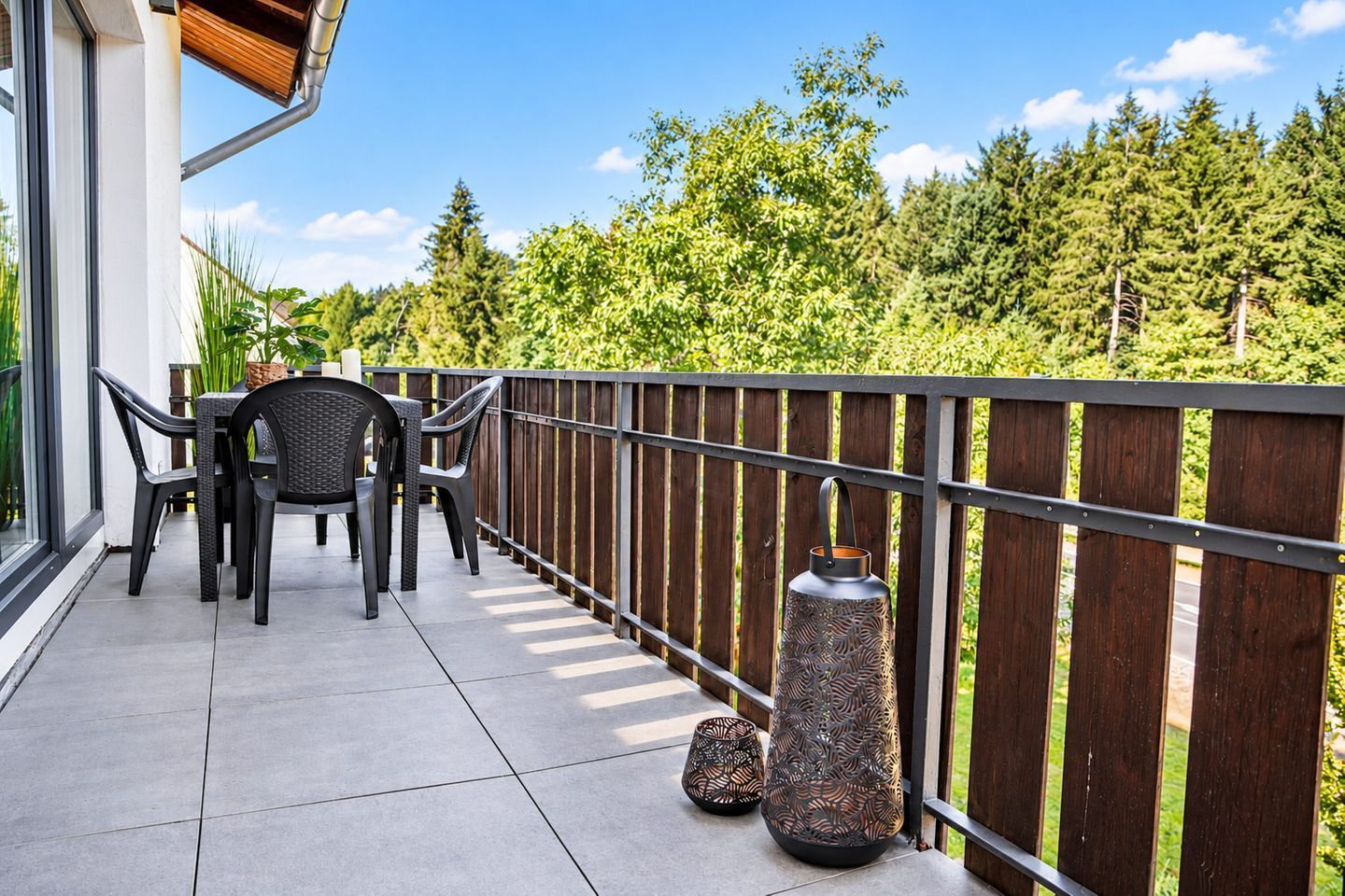 Un balcon avec une table et des chaises, une balustrade et une lanterne décorative.