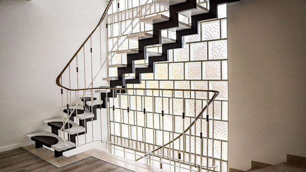 Eine moderne Treppe mit geometrischem Design, weißen Geländern und Holzboden.