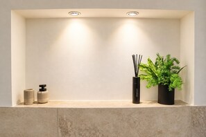Un tocador de baño con un accesorio de iluminación, un difusor y una planta en maceta.