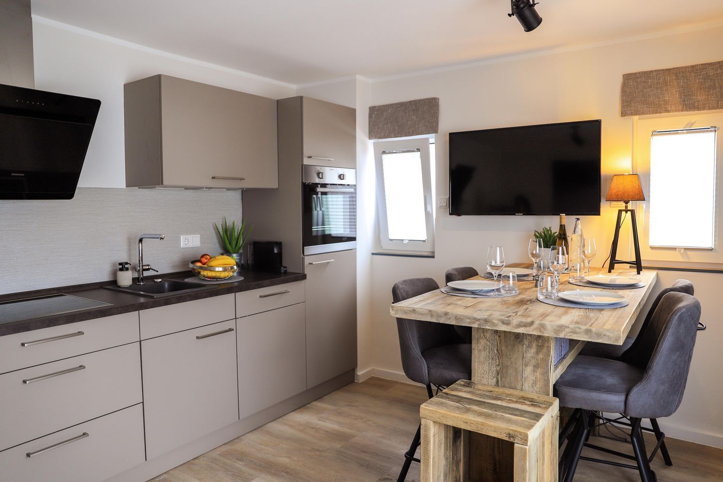 Een moderne keuken met een eethoek, inbouwapparatuur en een flatscreen televisie.