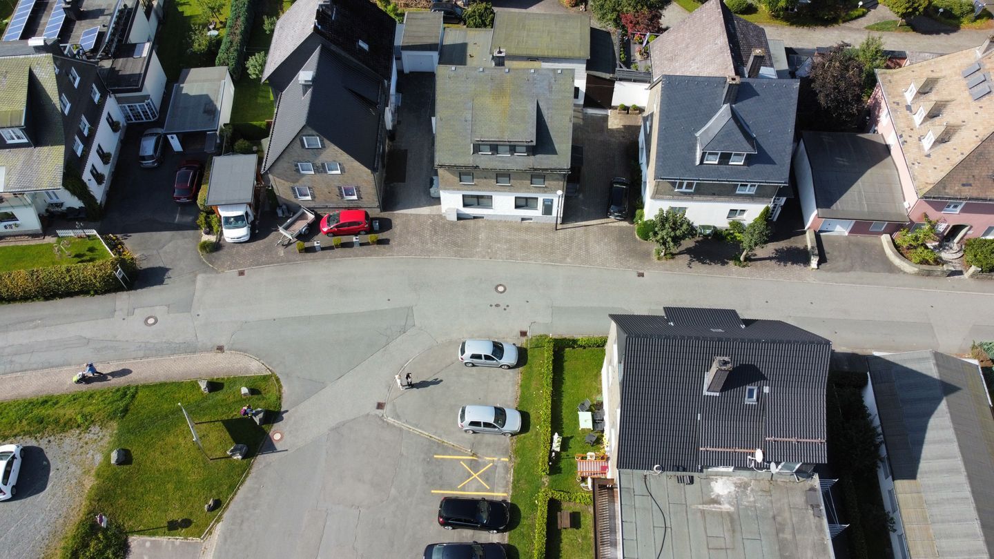 An aerial view of a residential area with houses, a parking lot, and a road.