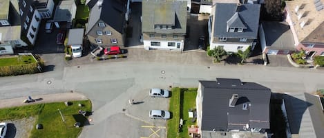 An aerial view of a residential area with houses, a parking lot, and a road.