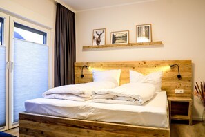 Un lit avec une tête de lit en bois, une literie blanche et deux lampes de chevet fixées au mur.