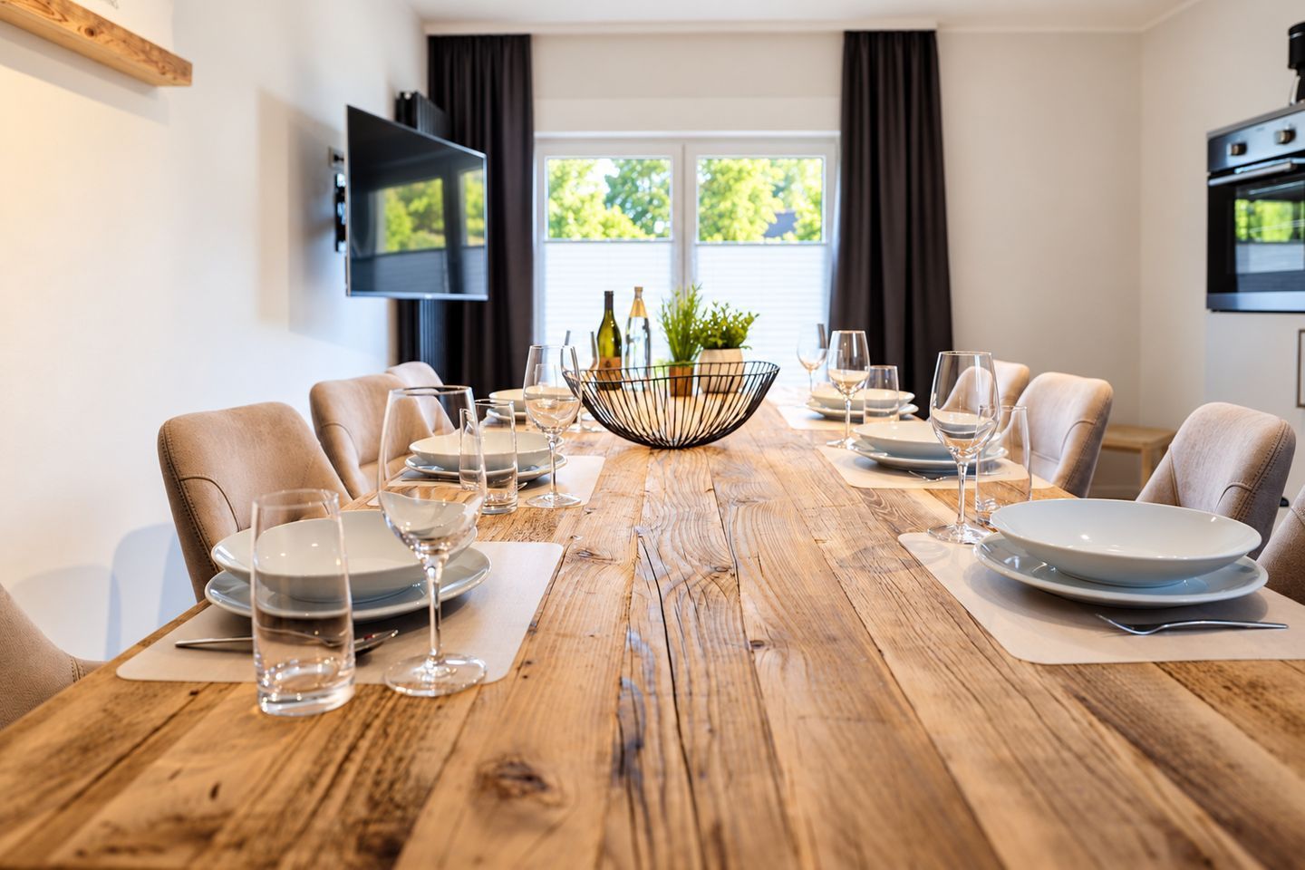 A dining table set for six with plates, glasses, and a centerpiece.