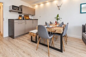 Eine moderne Küche mit Mikrowelle, Schränken und einem Essbereich mit Holztisch und Stühlen.