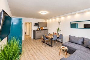 A compact living space with a dining area, kitchenette, and a seating area with a sofa and a small side table.