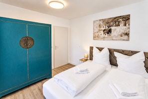 Ein Hotelzimmer mit einem Bett, einem Nachttisch, einem taubenfarbenen Wandschrank und einem Wandbild von einem Reh.