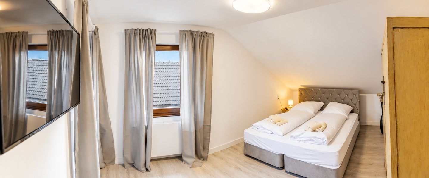 A bedroom with a bed, curtains, a window, and a door.