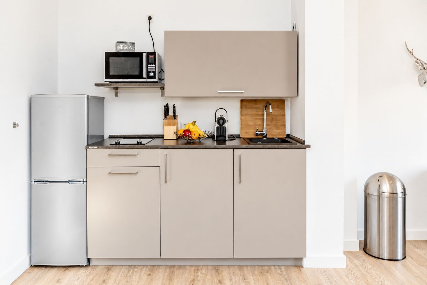 Une cuisine moderne équipée d’un réfrigérateur, d’un four à micro-ondes, d’un évier et de placards.