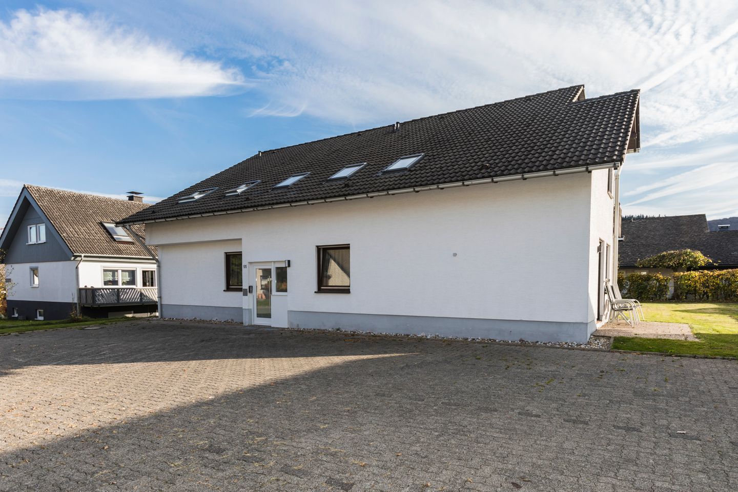 A single-story building with a tiled roof, a front door, and a small porch area.