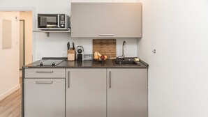 Eine moderne Küche mit grauen Schränken, einer Mikrowelle, einem Spülbecken und einer Obstschale.
