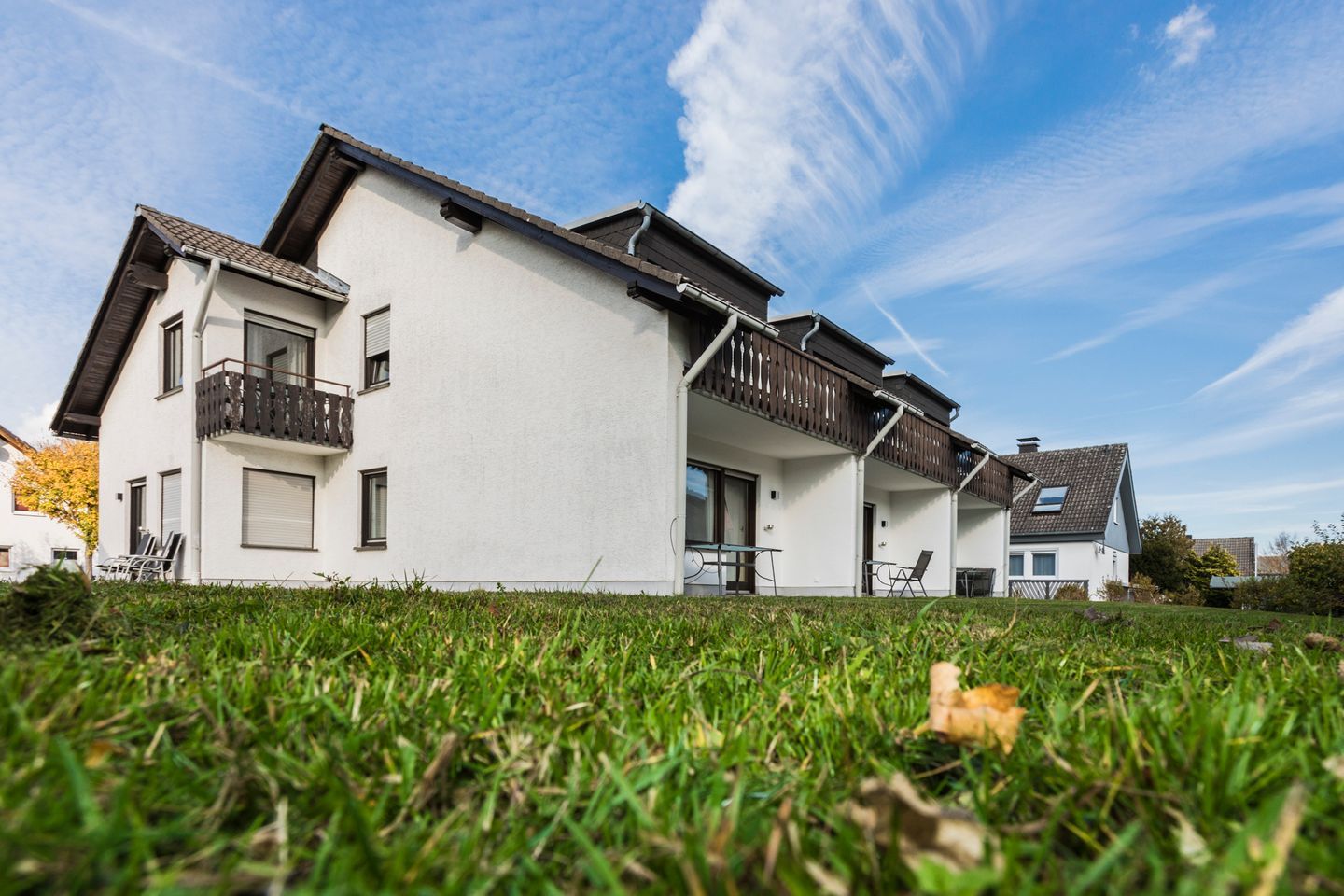 Un immeuble résidentiel de deux étages doté d’un balcon, d’un patio couvert et d’une pelouse devant.