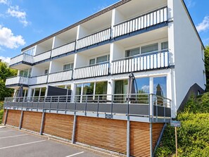 A multi-story hotel with balconies, a covered outdoor seating area, and a parking lot.