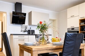 Una cocina moderna con una mesa de comedor de madera, sillas negras y un florero con flores.
