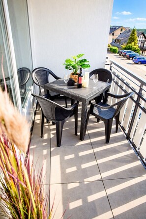 A balcony with a table and chairs, a potted plant, and a bottle of wine. - Smart Resorts - House Brilliant - Studio apartment 609 with balcony, max. 4 persons (Winterberg)
