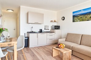 A compact living space with a kitchenette, a dining area, and a seating area with a view of the countryside. - Smart Resorts - House Brilliant - Studio apartment 609 with balcony, max. 4 persons (Winterberg)