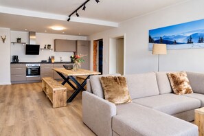 A modern living space with a sofa, a dining table, and a kitchen area.