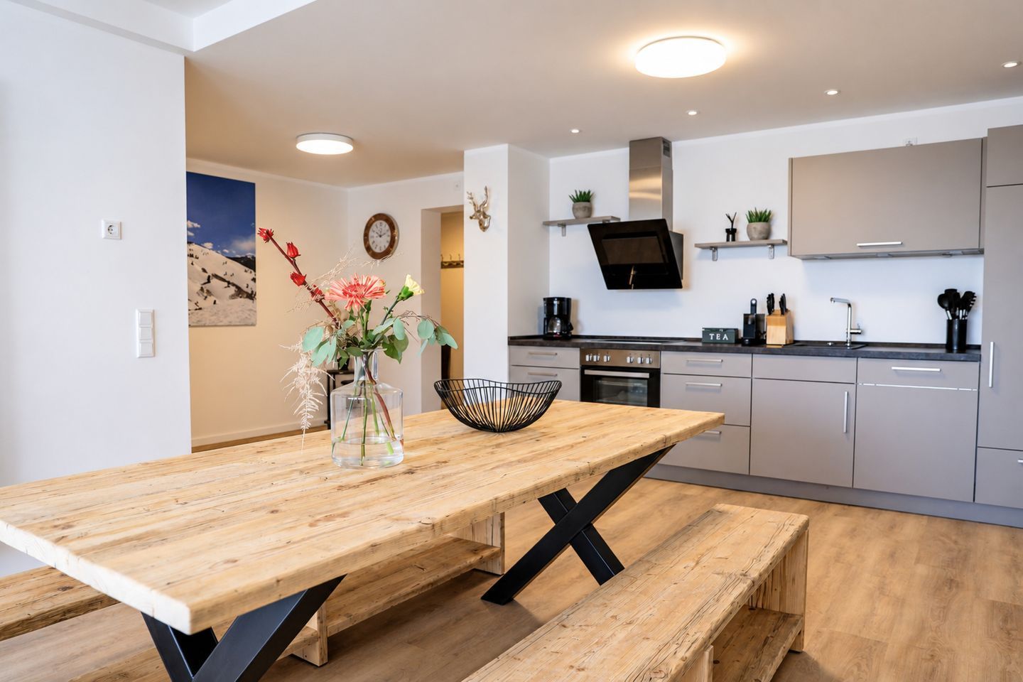 Una cocina moderna con una mesa de comedor de madera, un florero con flores y un cuenco negro.