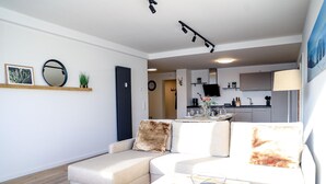 A modern living room with a sofa, a coffee table, and a kitchen in the background.