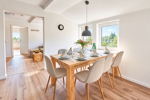 A dining area with a wooden table set for six, a modern pendant light, and a view of greenery outside. - Smart Resorts - Haus Saphir - Ferienwohnung 507 mit 2 Schlafzimmern, Max. 7 Personen - Smart Resorts (Winterberg)