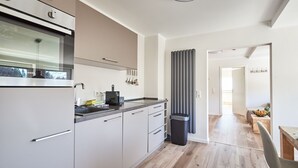 Eine moderne Küche mit Backofen, Kaffeemaschine und Mülleimer.
