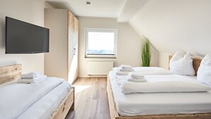 Ein modernes Hotelzimmer mit zwei Betten, einem großen Fenster, einem Flachbildfernseher und einer Heizung.
