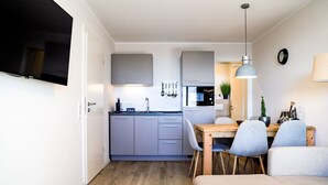 A compact living space with a kitchenette, dining area, and a TV mounted on the wall.