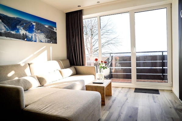 A modern living room with a sofa, a coffee table, and a painting on the wall.