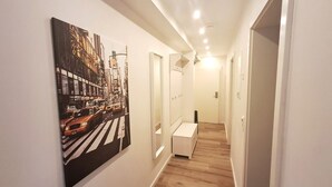A hallway with a cityscape painting, a white cabinet, and a wooden floor.