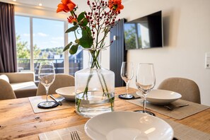 Una mesa de comedor con un florero, copas de vino y platos listos para una comida.