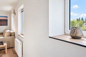 Una sala de estar moderna con un sofá, una mesa, un cuenco decorativo y vistas a árboles a través de una ventana.