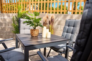 Un patio al aire libre con una mesa, sillas, una planta en maceta y velas.