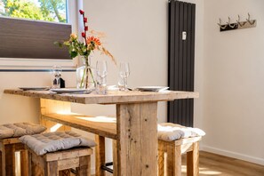 Ein Holztisch mit Bänken, klaren Gläsern und einer Blumenvase.