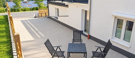 Un patio exterior con una mesa y sillas, un cerco de madera y una vista de paneles solares al fondo.