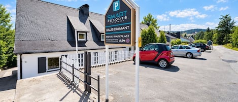 Un edificio con un letrero que dice 'SMART RESORTS WINTERBERG' y un estacionamiento con automóviles.