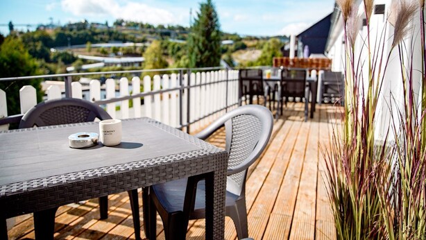 A wooden deck with outdoor furniture, a white fence, and a view of a hillside. - Smart Resorts - House Diamant - Apartment 705 with balcony, max. 5 persons - (Winterberg)